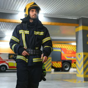 Fireman wearing protective uniform standing in fire department at fire station