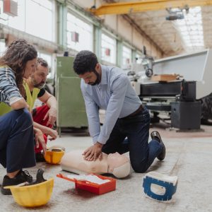 Male instructor showing first medical aid on doll during training course indoors
