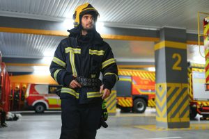 Fireman wearing protective uniform standing in fire department at fire station